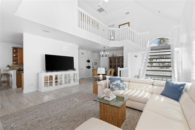 living room featuring light hardwood / wood-style floors, a high ceiling, and a chandelier