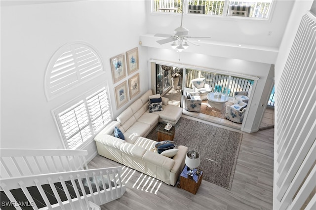 living room with light wood-type flooring, a high ceiling, and ceiling fan