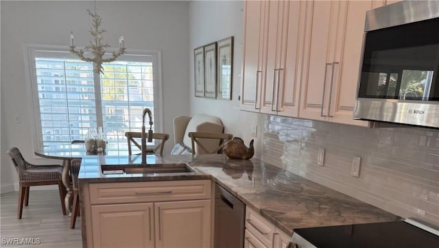 kitchen with sink, backsplash, stainless steel appliances, and an inviting chandelier