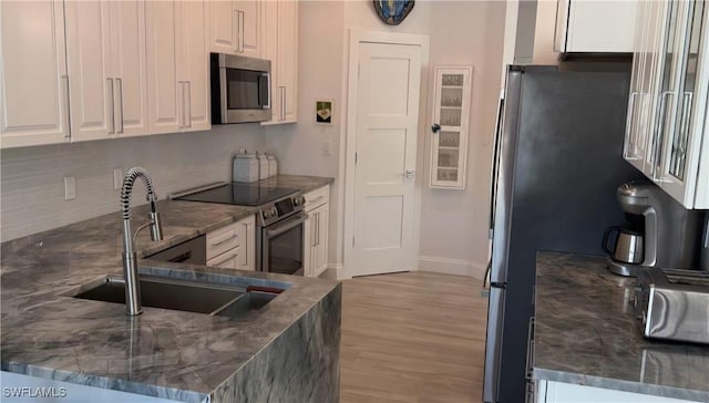 kitchen with light hardwood / wood-style floors, white cabinets, sink, kitchen peninsula, and stainless steel appliances