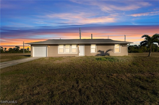 ranch-style house with a garage and a lawn