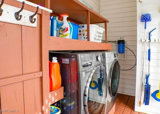 washroom with washing machine and dryer and wooden walls