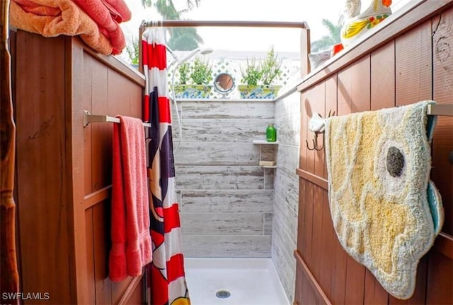 bathroom featuring wood walls and walk in shower