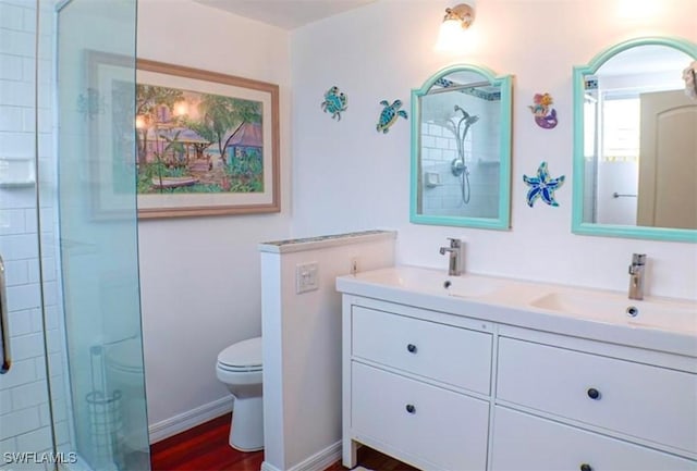 bathroom with hardwood / wood-style floors, vanity, toilet, and walk in shower