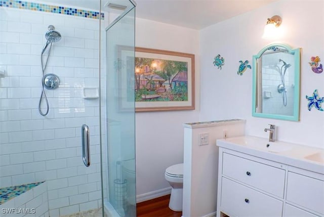 bathroom with an enclosed shower, vanity, toilet, and wood-type flooring