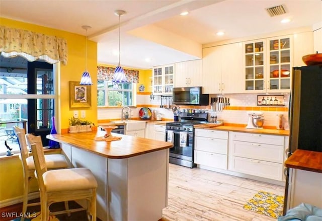 kitchen with decorative backsplash, decorative light fixtures, a kitchen bar, kitchen peninsula, and stainless steel appliances