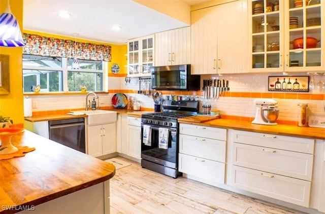 kitchen featuring sink, stainless steel appliances, tasteful backsplash, butcher block countertops, and light wood-type flooring