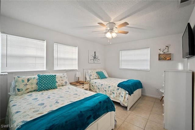 bedroom with multiple windows, light tile patterned floors, a textured ceiling, and ceiling fan