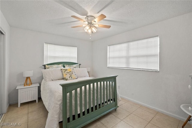 tiled bedroom featuring ceiling fan and a textured ceiling