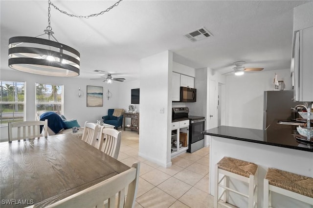 kitchen featuring ceiling fan with notable chandelier, sink, light tile patterned floors, white cabinetry, and stainless steel range with electric cooktop