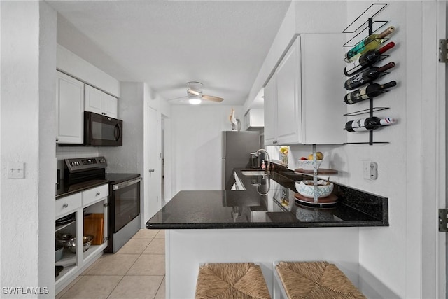 kitchen with kitchen peninsula, sink, appliances with stainless steel finishes, light tile patterned flooring, and white cabinetry