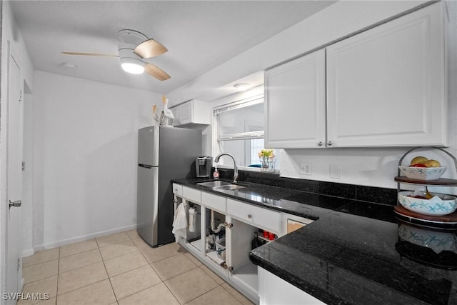 kitchen featuring ceiling fan, sink, dark stone countertops, white cabinets, and stainless steel refrigerator