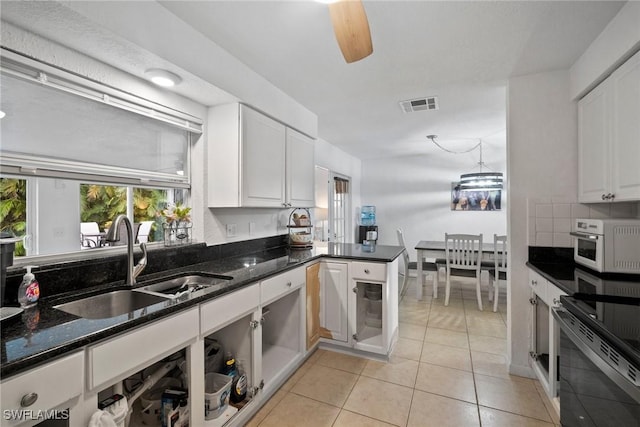 kitchen featuring white cabinetry, sink, light tile patterned floors, and dark stone counters