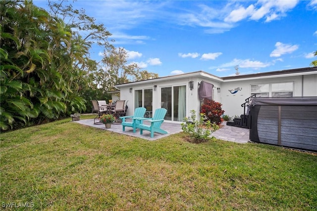 rear view of house with a patio area, a yard, and a hot tub