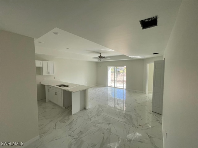 kitchen featuring ceiling fan, a center island, white cabinetry, and sink