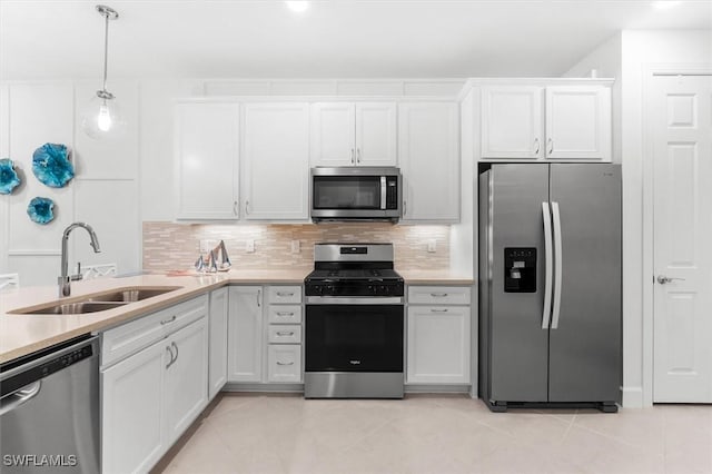 kitchen featuring appliances with stainless steel finishes, tasteful backsplash, sink, white cabinets, and hanging light fixtures