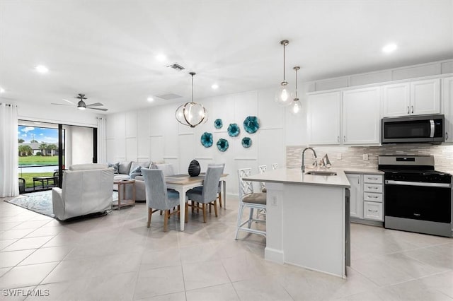 kitchen featuring pendant lighting, white cabinets, ceiling fan with notable chandelier, sink, and stainless steel appliances