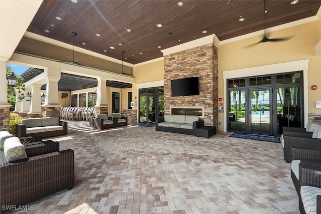 view of patio / terrace with an outdoor living space with a fireplace, ceiling fan, and french doors