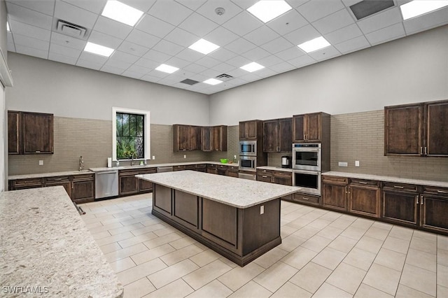 kitchen with dark brown cabinets, a kitchen island, and a towering ceiling