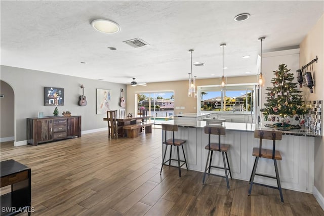 kitchen featuring dark hardwood / wood-style floors, ceiling fan, a breakfast bar area, and hanging light fixtures