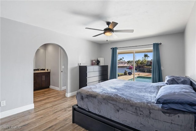 bedroom with ceiling fan, access to exterior, light wood-type flooring, and ensuite bath