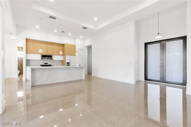 kitchen with french doors, sink, white fridge with ice dispenser, white cabinets, and hanging light fixtures