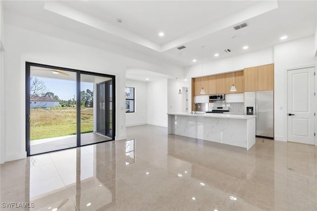 kitchen featuring a tray ceiling, sink, pendant lighting, and appliances with stainless steel finishes