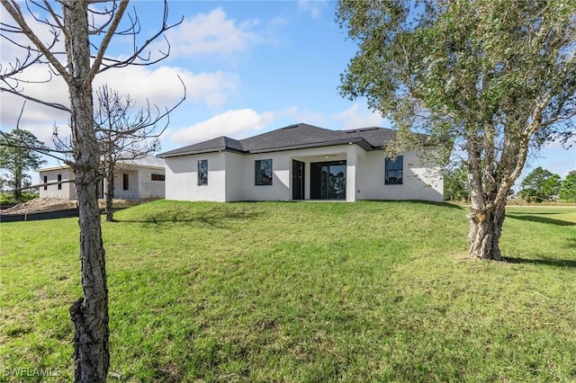 rear view of property featuring a lawn