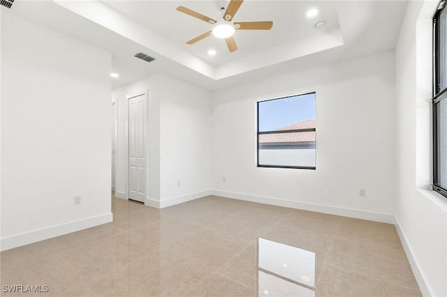 empty room featuring a tray ceiling and ceiling fan