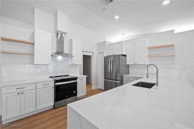 kitchen with wall chimney range hood, sink, white cabinetry, and appliances with stainless steel finishes