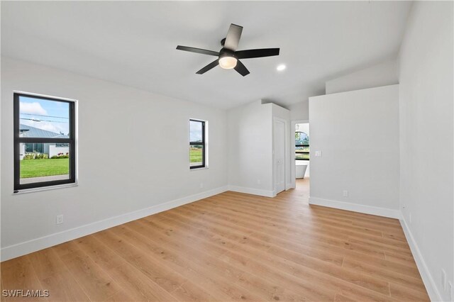 empty room with ceiling fan, light wood-type flooring, and lofted ceiling