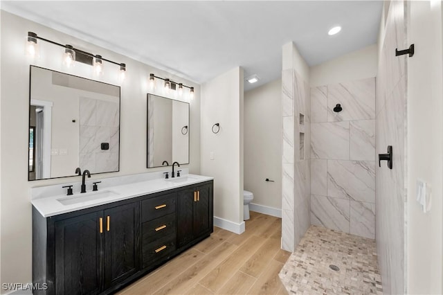 bathroom featuring toilet, vanity, and a tile shower