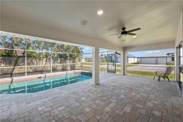 view of swimming pool with ceiling fan, a patio, and glass enclosure