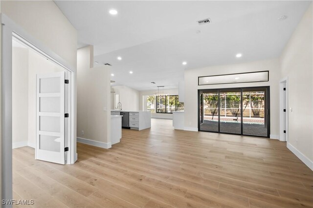 unfurnished living room with sink and light hardwood / wood-style flooring