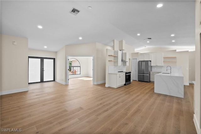 kitchen with white cabinets, electric stove, sink, stainless steel fridge, and light hardwood / wood-style flooring