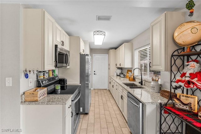 kitchen featuring white cabinetry, light stone countertops, sink, and appliances with stainless steel finishes