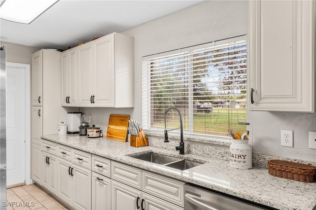 kitchen with light stone countertops, sink, light tile patterned floors, dishwasher, and white cabinetry