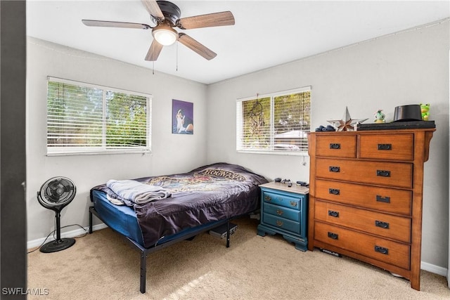 bedroom with multiple windows, ceiling fan, and light colored carpet