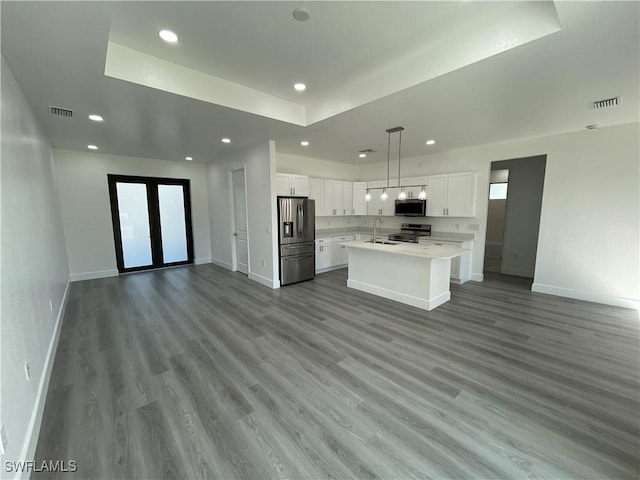 kitchen featuring white cabinetry, sink, stainless steel appliances, a kitchen island with sink, and light wood-type flooring