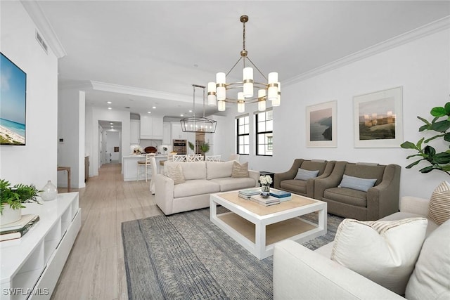 living room with crown molding, light hardwood / wood-style floors, and an inviting chandelier