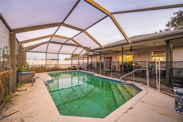 pool at dusk featuring a lanai, a patio area, and ceiling fan