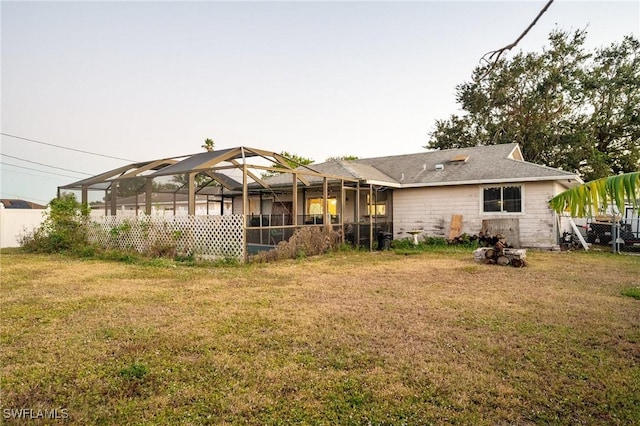 back of house with a lawn and glass enclosure