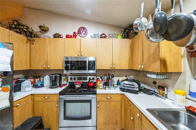 kitchen with a textured ceiling, sink, stainless steel appliances, and vaulted ceiling