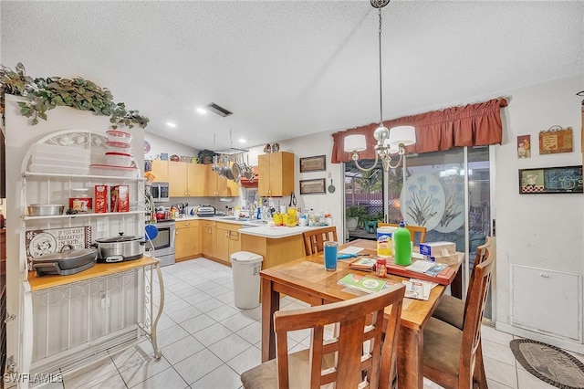 kitchen with pendant lighting, lofted ceiling, a textured ceiling, appliances with stainless steel finishes, and a notable chandelier