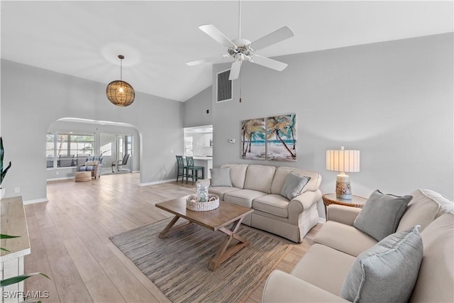 living room with light wood-type flooring, high vaulted ceiling, and ceiling fan