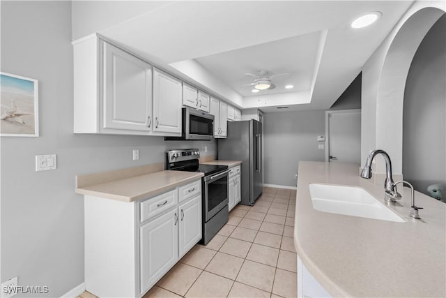 kitchen featuring sink, appliances with stainless steel finishes, a raised ceiling, ceiling fan, and white cabinets