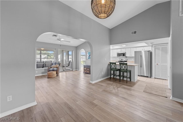 interior space featuring ceiling fan, high vaulted ceiling, and light hardwood / wood-style flooring