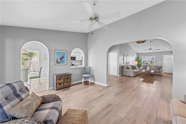 living room featuring plenty of natural light, light hardwood / wood-style flooring, ceiling fan, and vaulted ceiling