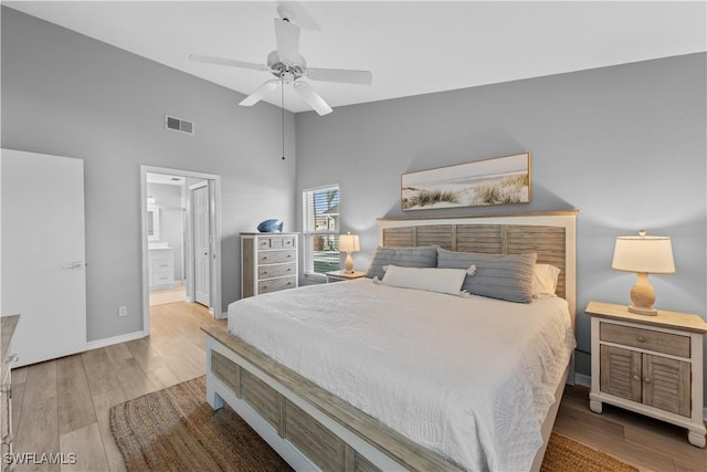 bedroom featuring ceiling fan, high vaulted ceiling, light wood-type flooring, and ensuite bath