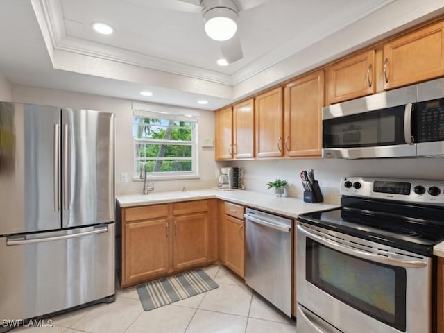 kitchen with a raised ceiling, sink, ornamental molding, light tile patterned floors, and stainless steel appliances